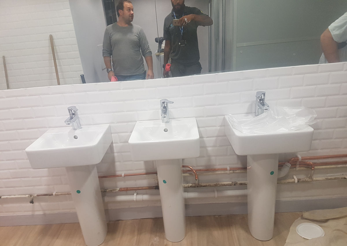 Twin basins and pipework during a commercial washroom installation