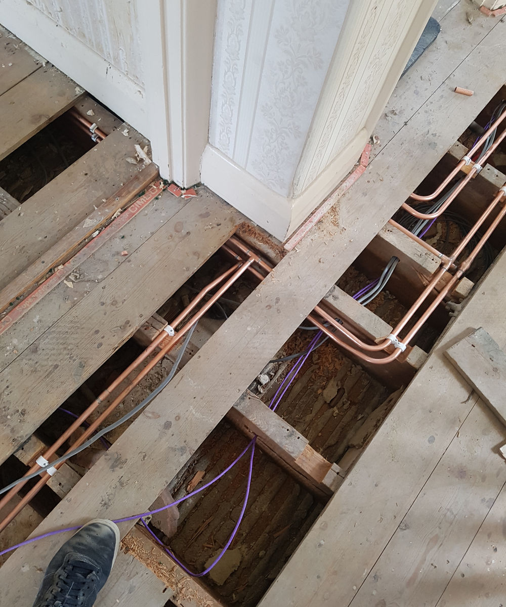Copper pipework routed below an existing timber floor
